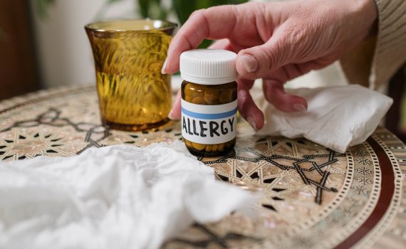 A close-up of allergy medication bottle on table with tissues, ideal for health themes.